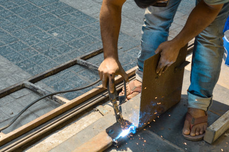 Worker cutting metal with electric arc welding machine at construction site.