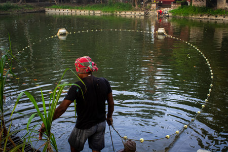 Fishermen are working in a calm pond, utilizing traditional fishing nets while surrounded by nature...