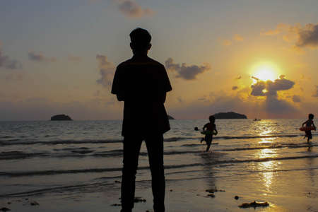 Lonely man stands on the beach looks towards the sun light,Steps on the sand, sunset, silhouette of...