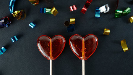 Heart-shaped sweets on a stick. Valentine's Day. Background. Candy on black background