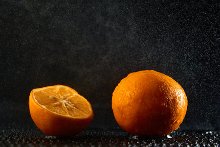 Orange halves with splashing water on blackの写真素材