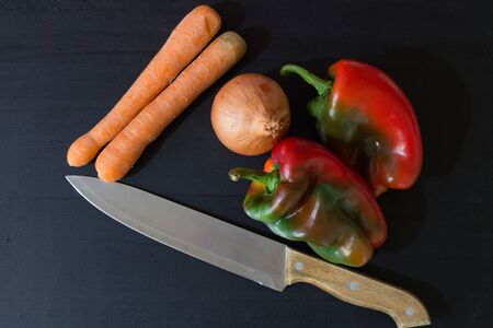 vegetables and knife on black wood