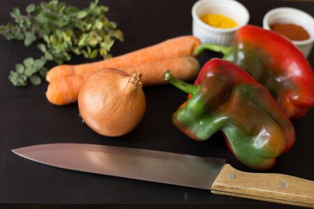 vegetables, spices and knife on black woodの写真素材