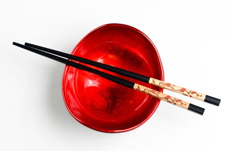 Two chop sticks and a red and black bowlの写真素材