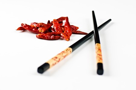 Chop sticks and some chili fruit on a white backgroundの写真素材