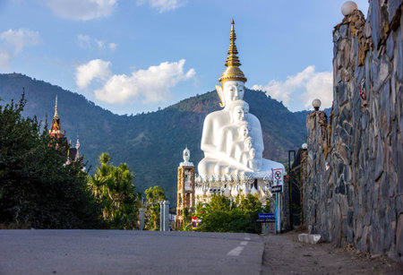 Road to white buddha statue and mountain background with blue sky in afternoon time.の写真素材