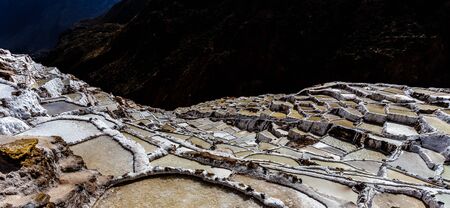 Since pre-Inca times, salt has been obtained in Maras by evaporating salty water from a local subterranean stream. The highly salty water emerges at a spring, a natural outlet of the underground stream. The flow is directed into an intricate system of tiny channels constructed so that the water runs gradually down onto the several hundred ancient terraced ponds.の写真素材
