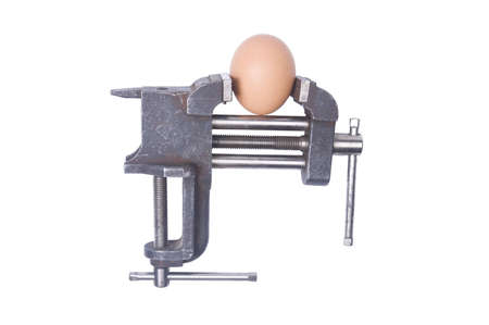 An egg in a vise under pressure. Isolated over white