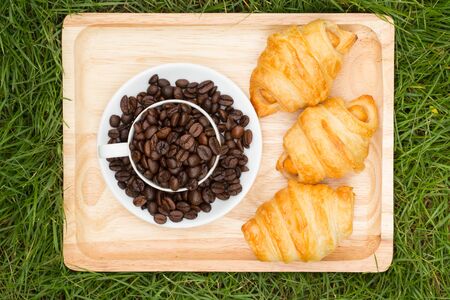 Croissants, sausage on a wooden tray and grass.の写真素材