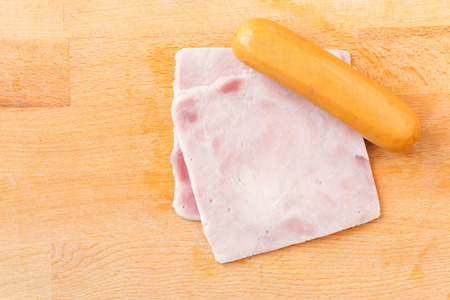 Ham and sausages on a wooden cutting boardの写真素材