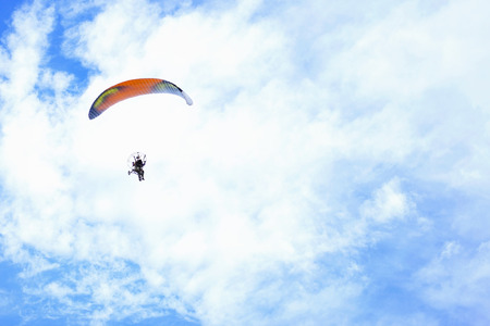 Paraglider flying in the blue sky against the background of clouds on the skyの写真素材