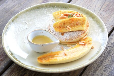 Pancakes with banana,hazelnut and caramel in the dish on the wooden table
surface,Delicious and healthyの写真素材