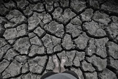 Barefoot standing on dry and cracked ground, gray, black and white