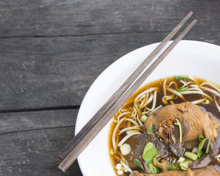 Thai style chicken noodle with soup on the vintage wooden background