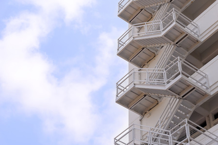 the fire escape stair which is a part of building with the sky and cloudの写真素材