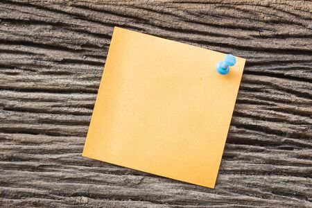 sticky paper note holding by pin on the old wooden backgroundの写真素材