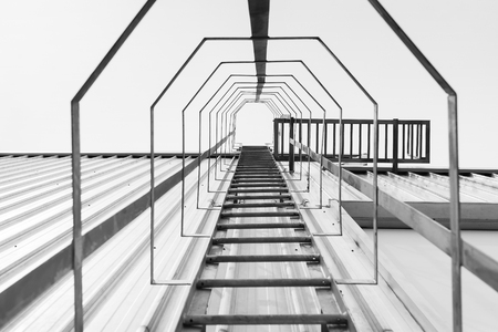 The fire escape,the fire escape stair with the upward scene.The black and white fire escape stair at the factory buildingの写真素材