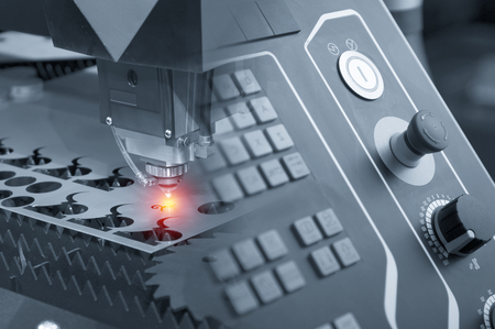 Abstract scene of the laser cutter machine with the controller panel  while cutting the sheet metal with the sparking light effect.の写真素材