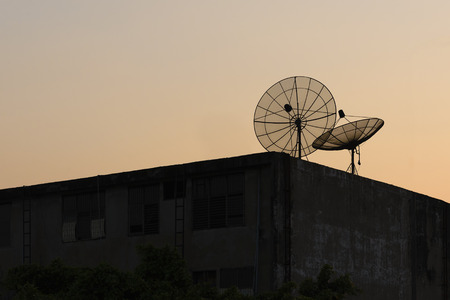 The TV satellite on the top of building with the silhouette sceneの写真素材