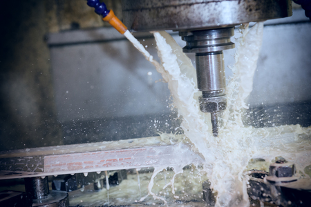 The CNC milling machine cutting the part with the coolant