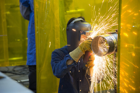 The welding craftsman grinding the steel tube and ware the safety mask.Safety working concept