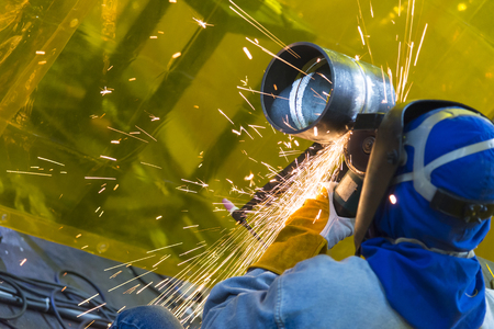 The welding craftsman grinding the steel tube and ware the safety mask.Safety working concept