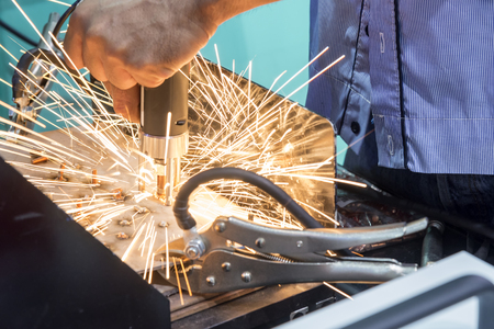 The spot welding machine with the sparking light.Worker spot the revet to the metal plate 