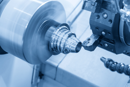 The CNC lathe machine cutting the metal cone shape part in the light blue scene.の写真素材