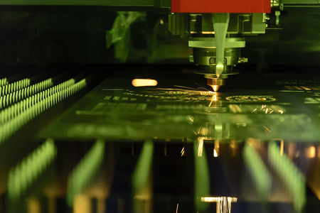 Close-up of the CNC laser cutting machine cutting the metal plate with the sparking light. Modern...