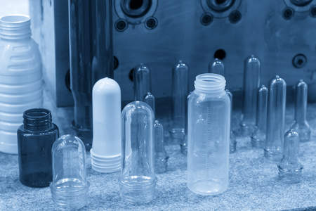 The various type of plastic bottle product and preform material with injection mold background. Drinking container manufacturing processing.の写真素材