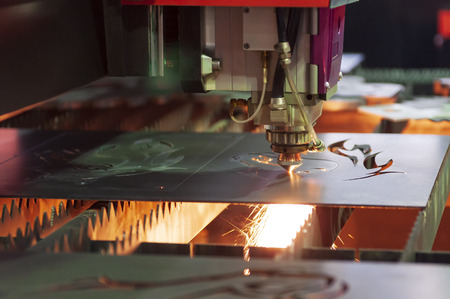 The CNC fiber laser cutting machine cutting the sheet metal plate  with the sparking light. Modern sheet metal manufacturing process.の写真素材