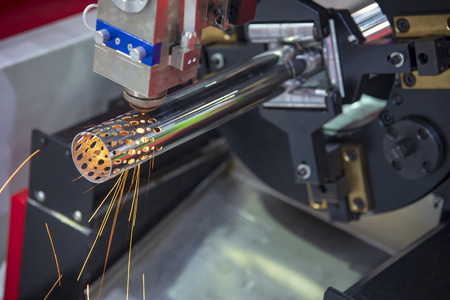 The CNC fiber laser cutting machine cutting the stainless   pipe or tube  with the sparking light. Modern sheet metal manufacturing process.の写真素材