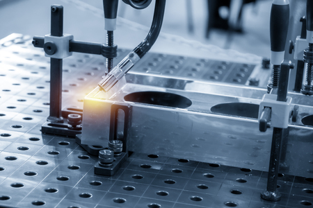 The welding robot machine for welding automotive part in the light blue scene.Industrial 4.0 concept for modern manufacturing process.の写真素材