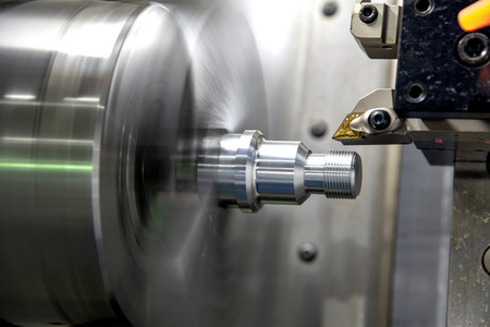 The CNC lathe machine cutting the thread    at the metal parts. The hi-technology automotive parts manufacturing process by turning machine.の写真素材
