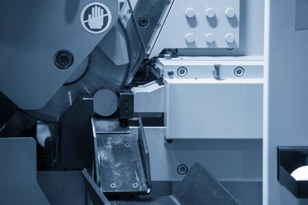 The band saw machine cutting the metal rod. The metal working with the automatic band saw machine.
