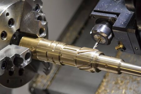 The CNC lathe,multi-tasking machine cutting the groove  slot at the brass shaft with the milling spindle by solid endmill tools. Metal working process by CNC turning machine for automotive industrial.の写真素材