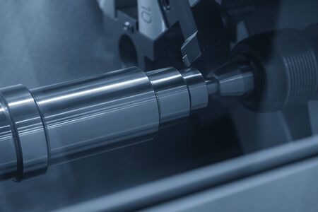 The CNC lathe machine in metal working process cutting the metal shaft parts with the cutting tools....