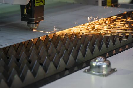 The fiber laser cutting machine cutting the sheet metal  plate with the sparkling light.  The...