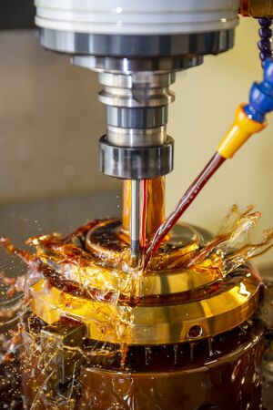 The CNC milling machine cutting the tire mold parts with liquid oil coolant method in vertical scene. The mold and die manufacturing process by CNC machining center.の写真素材
