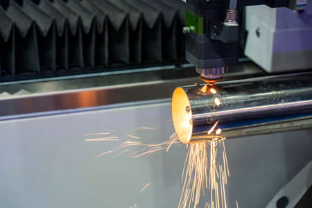 The fiber laser cutting machine cutting the stainless steel tube control by CNC program. The sheet metal working processing by laser cutting machine make the engrave at the stainless steel pipe parts.の写真素材