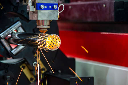 The fiber laser cutting machine cutting the stainless steel tube control by CNC program. The sheet metal working processing by laser cutting machine make the engrave at the stainless steel pipe parts.の写真素材