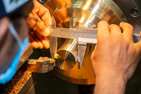 The machine operator measure the dimension of brass shaft by Vernier caliper. The quality control process of hi-precision parts manufacturing process.の写真素材
