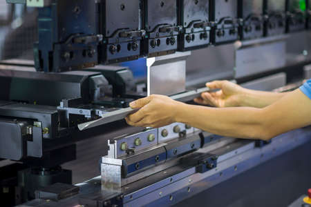 The technician operator working with hydraulic press brake bending machine. The sheet metal working...