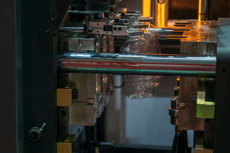 The plastic drinking bottles in the  blowing mold machine. The operation of PET bottle processing by...