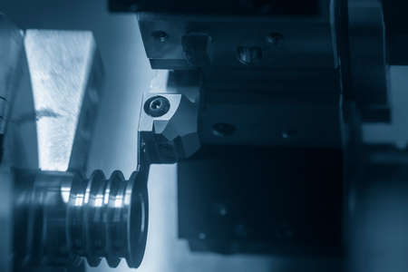 The  CNC lathe machine groove cutting the metal pulley parts with lighting  effect. The hi-technology automotive parts manufacturing process by CNC turning machine .の写真素材