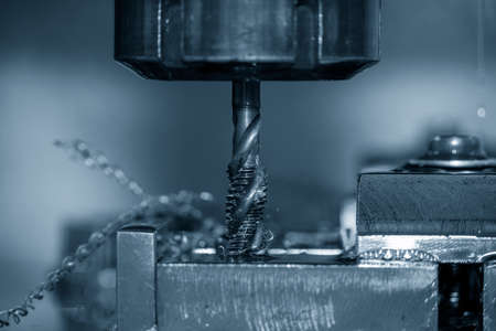 The closeup scene of machine tapping process on CNC machine. The threading process on machining...