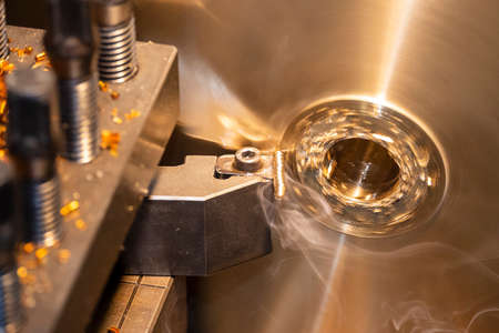 Closeup scene the lathe machine rough cutting the brass disk parts by lathe tools. The metalworking...