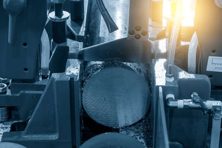 Close up scene the band saw machine cutting the metal rod with lighting effect. The machine tool for industrial purpose.の写真素材