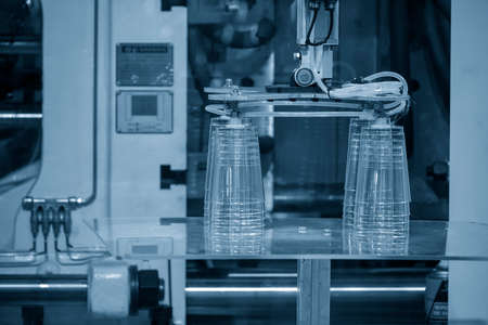 The robotic arm gripping the plastic cup from the injection machine. The high technology automatic...