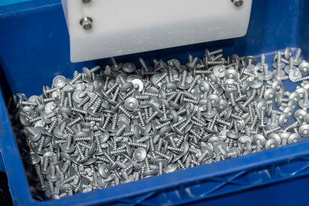 The pile of special screw in the container box. The hardware for construction industry.